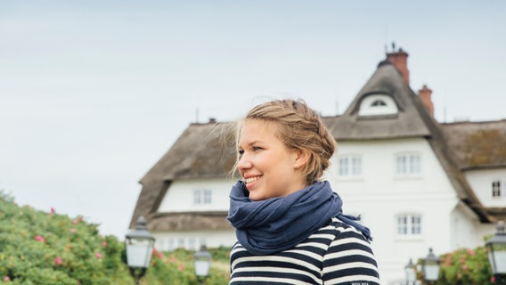 Foodbloggerin Theresa Baumgärtner steht vor einem reetgedeckten Haus auf Sylt. © NDR Foto: Claudia Timmann
