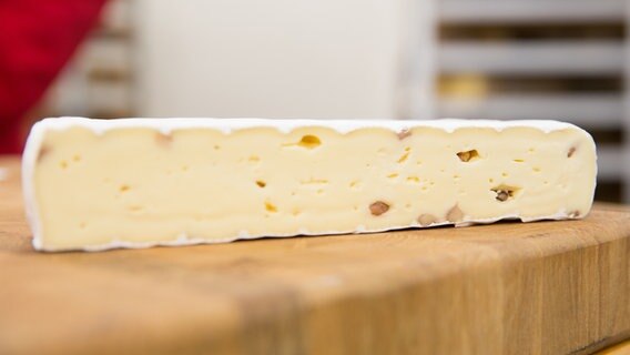 Ein Stück Walnuss-Brie auf einem dicken Holzbrett. © NDR Foto: Claudia Timmann