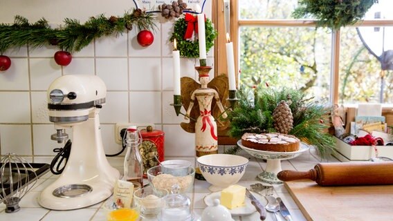 In einer weihnachtlich geschmückten Küche stehen eine Teigrührmaschine und verschiedene Zutaten zum Backen. © NDR Foto: Claudia Timmann