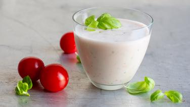 Tomaten-Buttermilch-Shake in einem Glas. Daneben liegen Tomaten und Basilikumblätter. © NDR Foto: Claudia Timmann