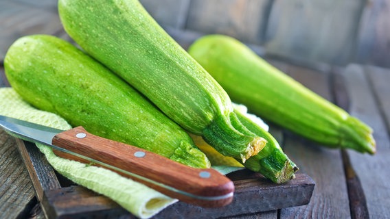 Frische Zucchini liegen auf einem Brett, daneben ein Messer. © Colourbox Foto: Y. Haivoronska
