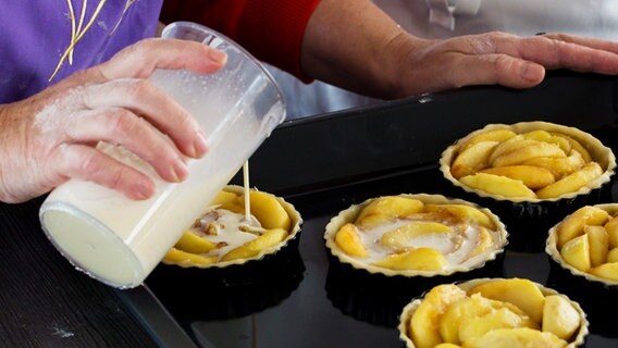 In kleine Förmchen mit Kuchen wird Eiersahne-Mischung gefüllt © NDR Foto: Claudia Timmann