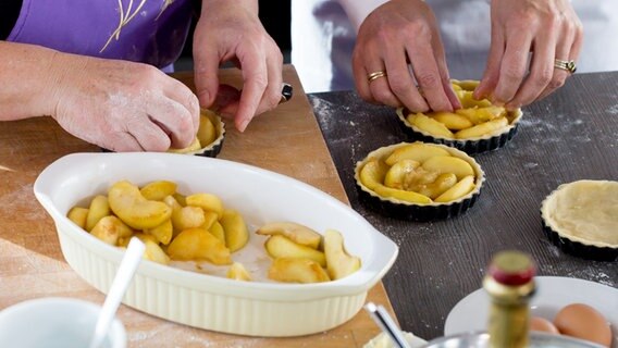 Kleine Mürbeteigkuchen werden mit Apfelspalten belegt © NDR Foto: Claudia Timmann