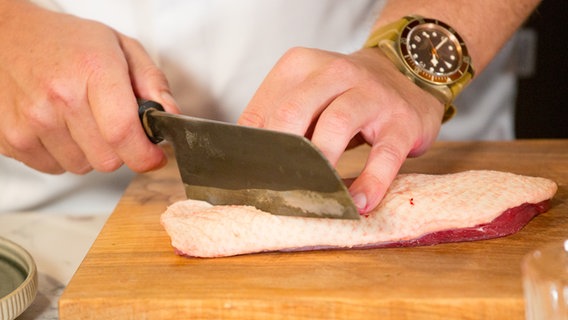 Die Haut einer Entenbrust wird mit einem Messer eingeschnitten. © NDR Foto: Claudia Timmann