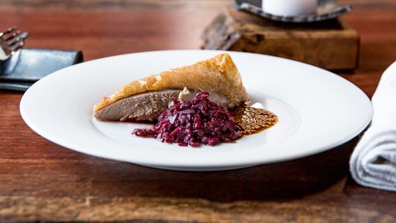 Eine Stück Entenbrust mit Rotkohl und Senfsaatjus auf einem weißen Porzellanteller. © NDR Foto: Claudia Timmann