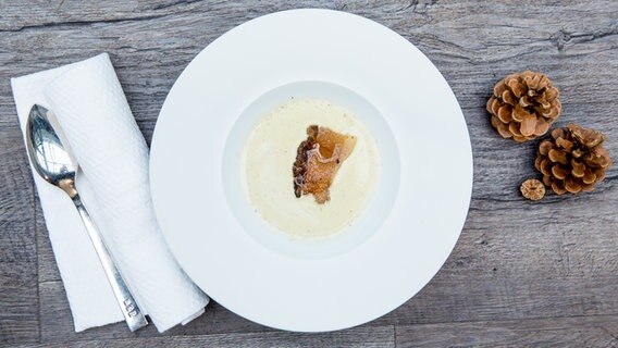 Rosenkohlsuppe mit gebratenem Holsteiner Speck auf einem Teller. © NDR Foto: Claudia Timmann