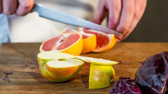 Ein Apfel und eine Orange werden klein geschnitten. © NDR Foto: Claudia Timmann