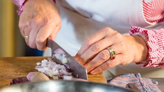 Eine Köchin schneidet eine Zwiebel in kleine Würfel. © NDR Foto: Claudia Timmann