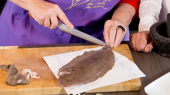 Eine Köchin schneidet die Haut einer Seezunge ein © NDR Foto: Claudia Timmann