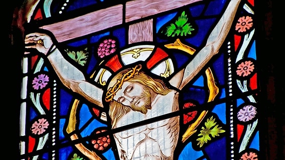 Ein farbiges Kirchenfenster zeigt Jesus Christus am Kreuz. © imago images / ingimage 