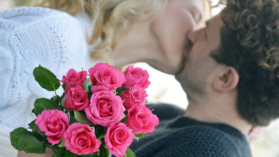 Ein paar küsst sich, im Vordergrund ein Strauß Rosen © picture alliance/Susann Prautsch/dpa Foto: Susann Prautsch