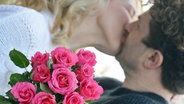 Ein paar küsst sich, im Vordergrund ein Strauß Rosen © picture alliance/Susann Prautsch/dpa Foto: Susann Prautsch