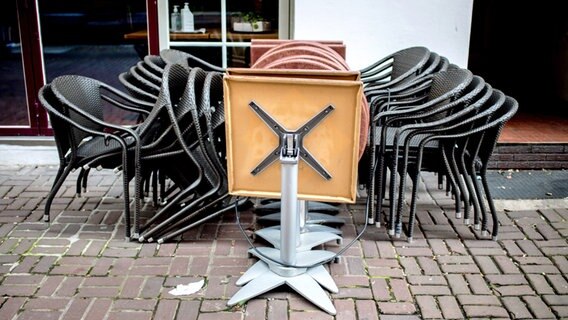 Aufgestapelte Stühle und zugeklappte Tische stehen vor einem wegen Corona geschlossenen Restaurant. © dpa-Bildfunk Foto: Hauke-Christian Dittrich