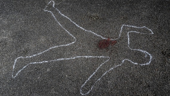 Der Umriss einer Person ist mit Kreide auf den Asphalt gemalt. © photocase Foto: bernjuer