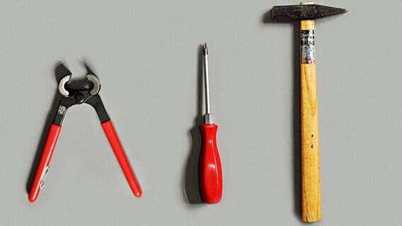 Zange, Schraubendreher und Hammer liegen auf einem grauen Untergrund. © photocase Foto: suschaa