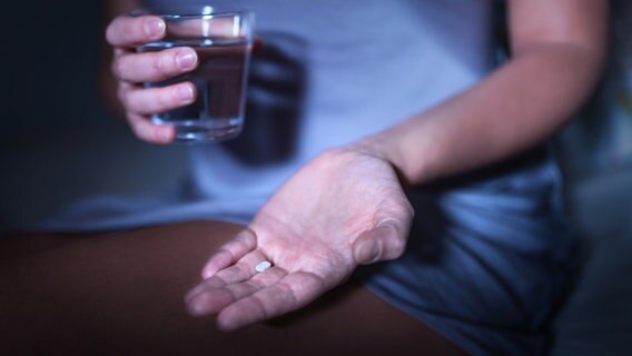 Eine Hand hält eine Tablette, die andere ein Glas Wasser. © Colourbox Foto: -