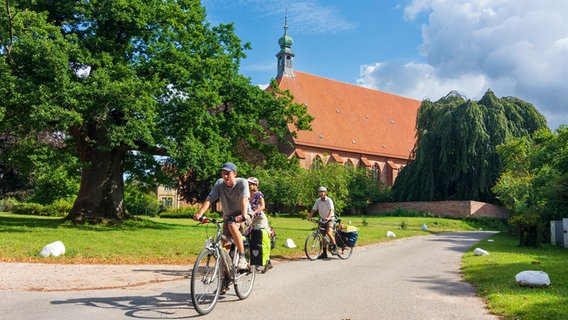 Eine kleine Gruppe von Rad fahrenden Menschen vor einer Kirche in Preetz. © Imago Foto: Volker Preußer