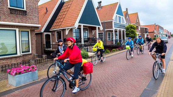 Eine Gruppe von älteren Menschen fahren mit dem Fahrrad durch einen Ort mit niederländischer Anmtung. © colourbox Foto: -