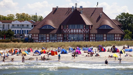 Strandmuscheln und Urlauber am Strand von Zingst, im Hintergrund das Kurhaus. © imago images / imagebroker 