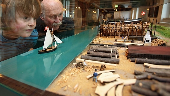 Besucher blicken auf ein Modell im Flensburger Schifffahrtsmuseum © Flensburger Schifffahrtsmuseum 