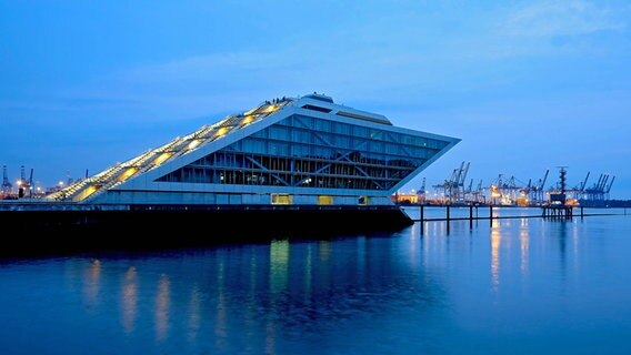 Blick auf das Bürogebäude Dockland mit Aussichtsterrasse und die Hafenanlagen an der Elbe in Hamburg am Abend. © imago images/Shotshop 