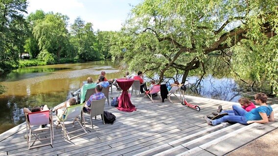 Besucher der Gartenschau in Hamburg-Wilhelmsburg sitzen auf einer Terrasse am Wasser. © igs 2013 Foto: Andreas Bock