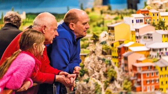 Zwei Erwachsene und ein Mädchen betrachten ein Detail im Italien-Abschnitts des Miniatur Wunderlandes in Hamburg. © Miniatur Wunderland Hamburg 