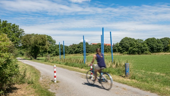 Eine Radfahrerin fährt an blauen Stehlen vorbei © Region Hannover 