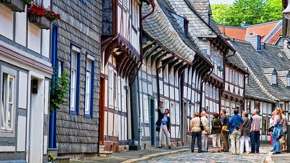 Touristen stehen bei einer Stadtführung vor einem Fachwerkhaus in Goslar. © GOSLAR marketing gmbh 