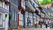 Touristen stehen bei einer Stadtführung vor einem Fachwerkhaus in Goslar. © GOSLAR marketing gmbh 