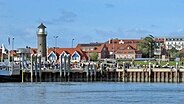 Hafen, Leuchtturm und Häuser hinter dem Deich auf der Insel Juist © imago images / sepp spiegl Foto: Sepp Spiegl