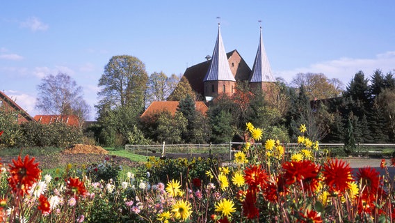 Blick auf den Dom in Bardowick, davor Blumen. © imago images / Shotshop 