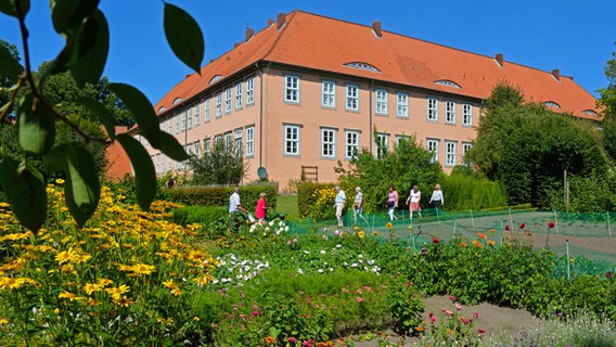 Blick auf das  Kloster Isenhagen und seinen Garten mit Besuchern. © imago images Foto: Wolf Winter