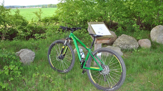 Ein Fahrrad lehnt an einer Box am Feldrand  