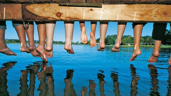 Kinder sitzen auf einem Bootssteg und lassen die Beine baumeln. © Tourismusverband Mecklenburg-Vorpommern Foto: Werk 3 - Agentur für PR