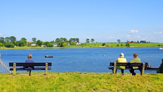 Vacationers sit on benches and look at an inlet near Kirchdorf auf Poel © imago/imagebroker 