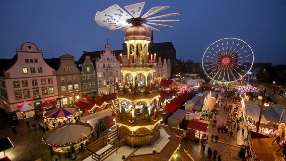 Blick über den Rostocker Weihnachtsmarkt mit der großen begehbaren Weihnachtspyramide. © picture alliance/ZB Foto: Bernd Wüstneck