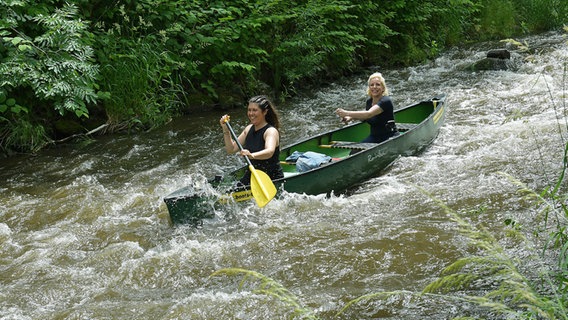 Die Reporterinnen Vanessa Kossen und Britta von Lucke paddeln durch wildes Wasser auf der Oker. © NDR/dmfilm Foto: Michael Bahlo