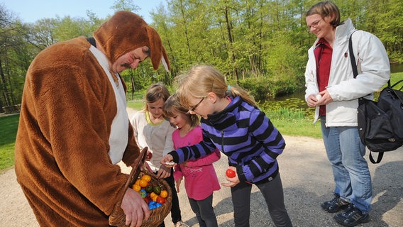 Ein als Osterhase verkleideter Mitarbeiter verteilt in einem Tierpark Ostereier an Kinder. © Imago / Funke Foto Services Foto: Diana Roos/WAZ FotoPool