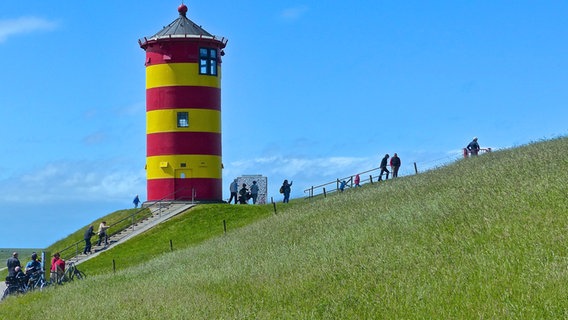 Menschen laufen auf dem Deich am Pilsumer Leuchtturm © L. Kalkhoff Foto: L. Kalkhoff