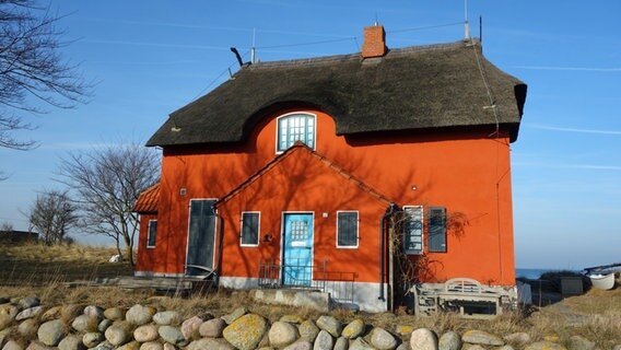 Orangefarbenes Haus mit Reetdach auf der Halbinsel Graswarder in Heiligenhafen. © NDR Foto: Kathrin Weber