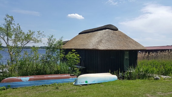 Zwei Boote liegen vor einem reetgedeckten Bootshaus in Zarrentin am Schaalsee. © NDR Foto: Kathrin Weber