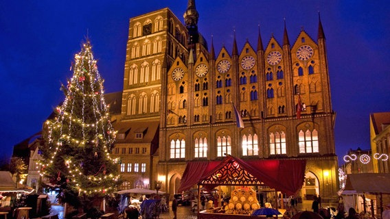 Weihnachtsmarkt vor dem beleuchteten Rathaus von Stralsund © imago/Jens Koehler 