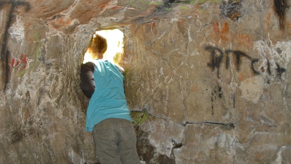 Ein Kind schaut durch ein Felsloch in der Lippoldshöhle im Glenetal © NDR Foto: Axel Franz