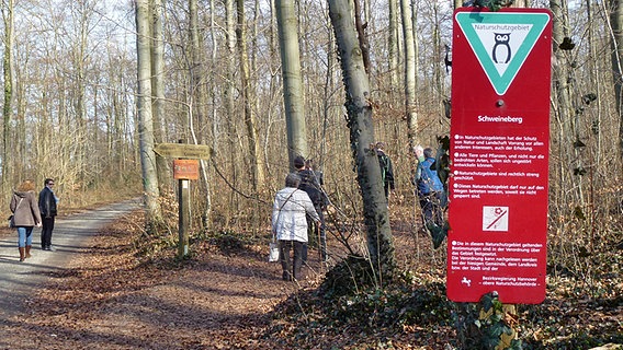 Spaziergänger und ein Hinweisschild am Naturschutzgebiet Schweineberg bei Hameln © NDR Foto: Axel Franz