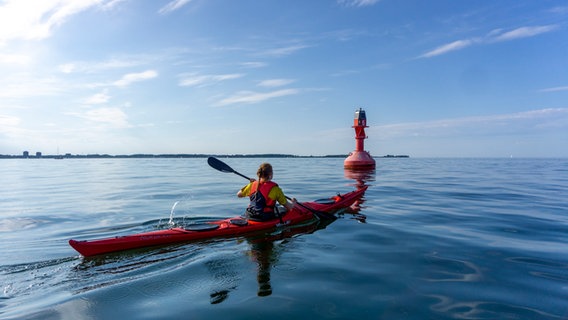Eine Seekajakfahrerin paddelt an einer roten Fahrwassertonne vorbei.  Foto: Eike Köhler