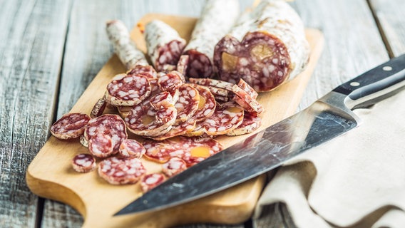 Eine Salami, Salamistücke und ein Messer liegen auf einem Schneidebrett. © COLOURBOX Foto: Jiri Hera