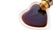 Eine braune Sauce wird aus einer Glasflasche in ein kleines weissen Porzellanschälchen gegossen. © fotolia.com Foto: gamjai