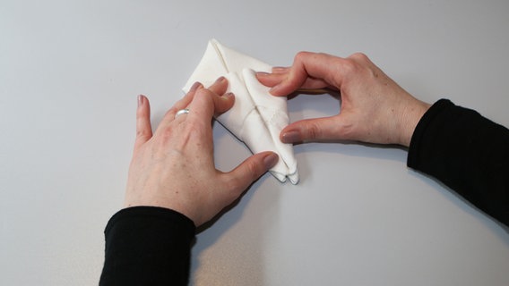 Hände falten eine Serviette. © NDR Foto: Anja Deuble