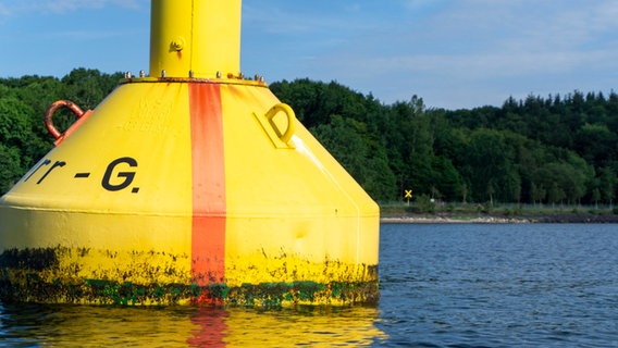 Eine gelb-rote Tonne im Vordergrund markiert mit einem gelben Kreuz an Land den Rand eines Sperrgebiets.  Foto: Eike Köhler
